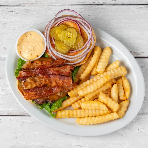 Bacon cheeseburger with lettuce, tomato, onion, pickles, and a side of crinkle-cut fries and dipping sauce.